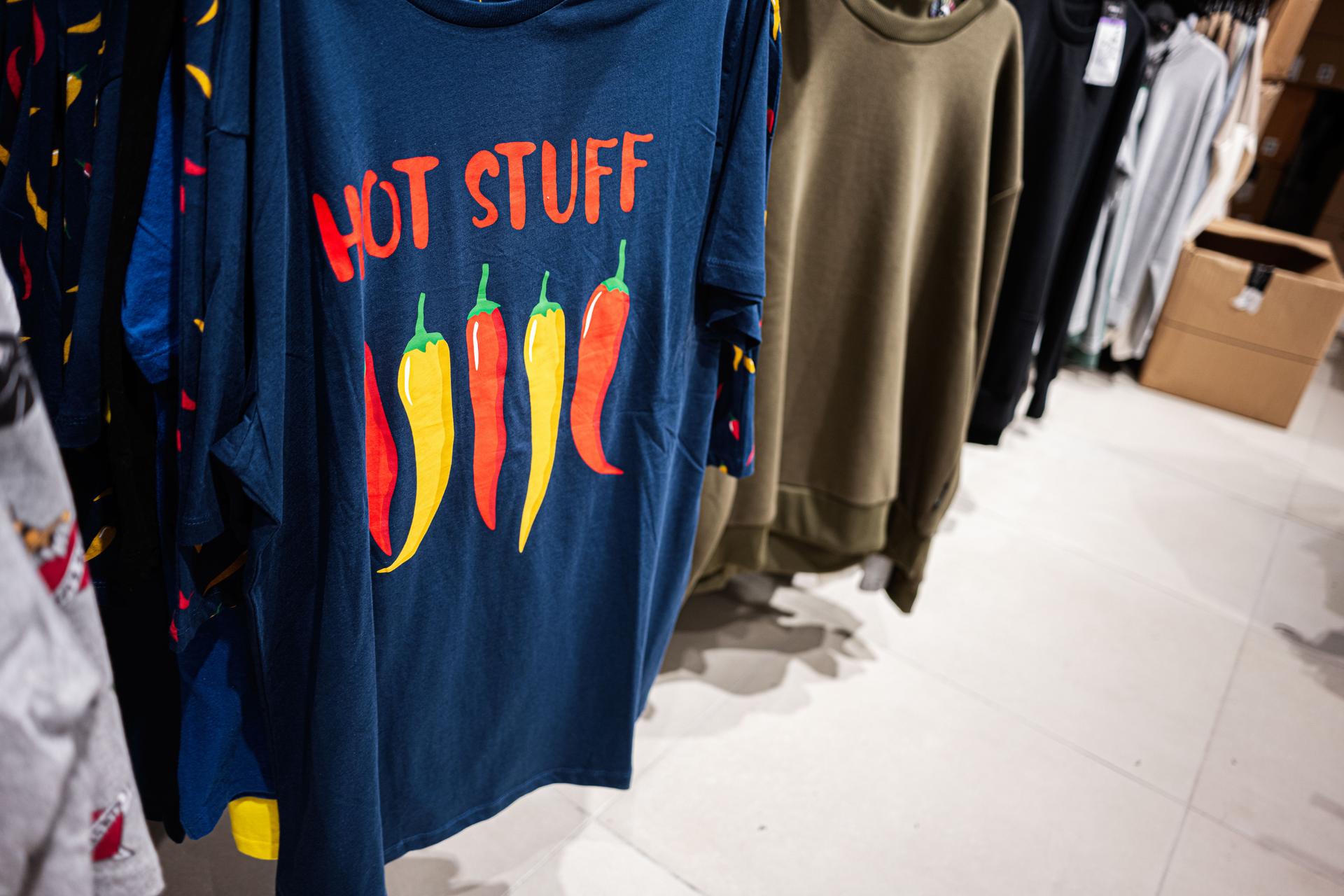 Blue t-shirt with chili Hot Stuff print and vibrant lettering in a retail environment