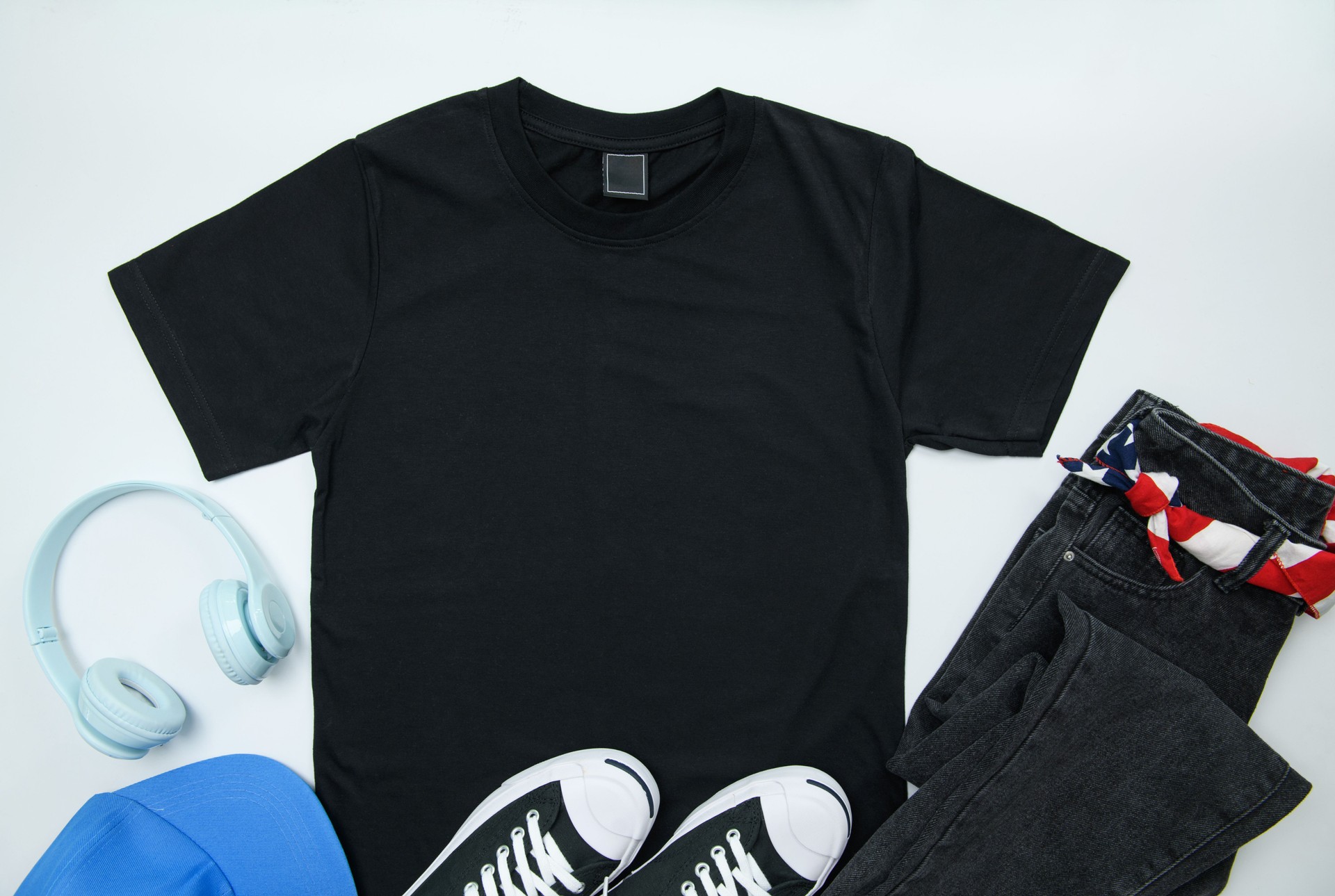 Blank black womens cotton Tshirt mockup with jeans and canvas shoes, head phone isolated on white background. Design t shirt template, print presentation mockup. Top view flat lay.